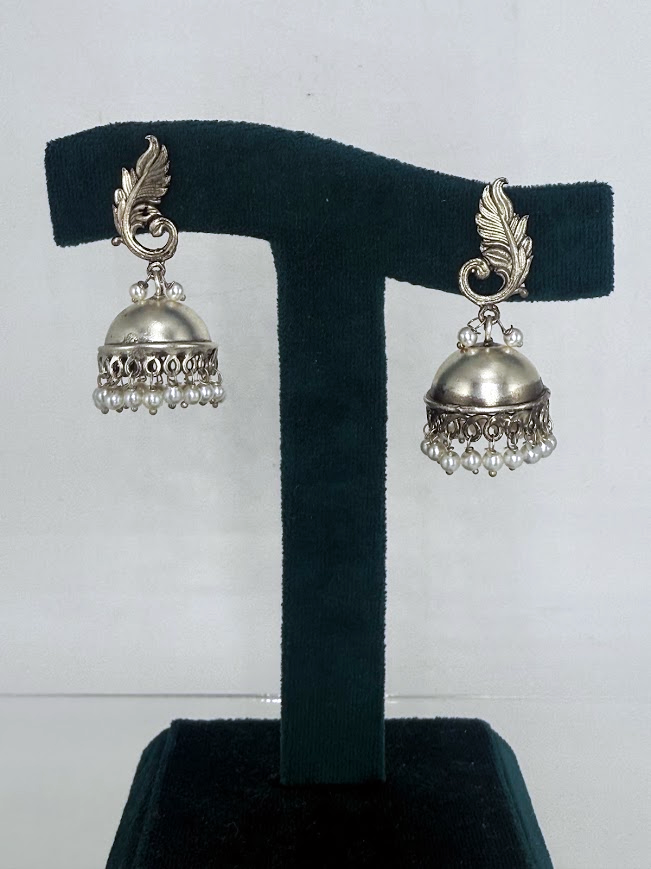 A pair of silver-toned Indian jhumka earrings displayed on a black velvet T-stand against a white background.