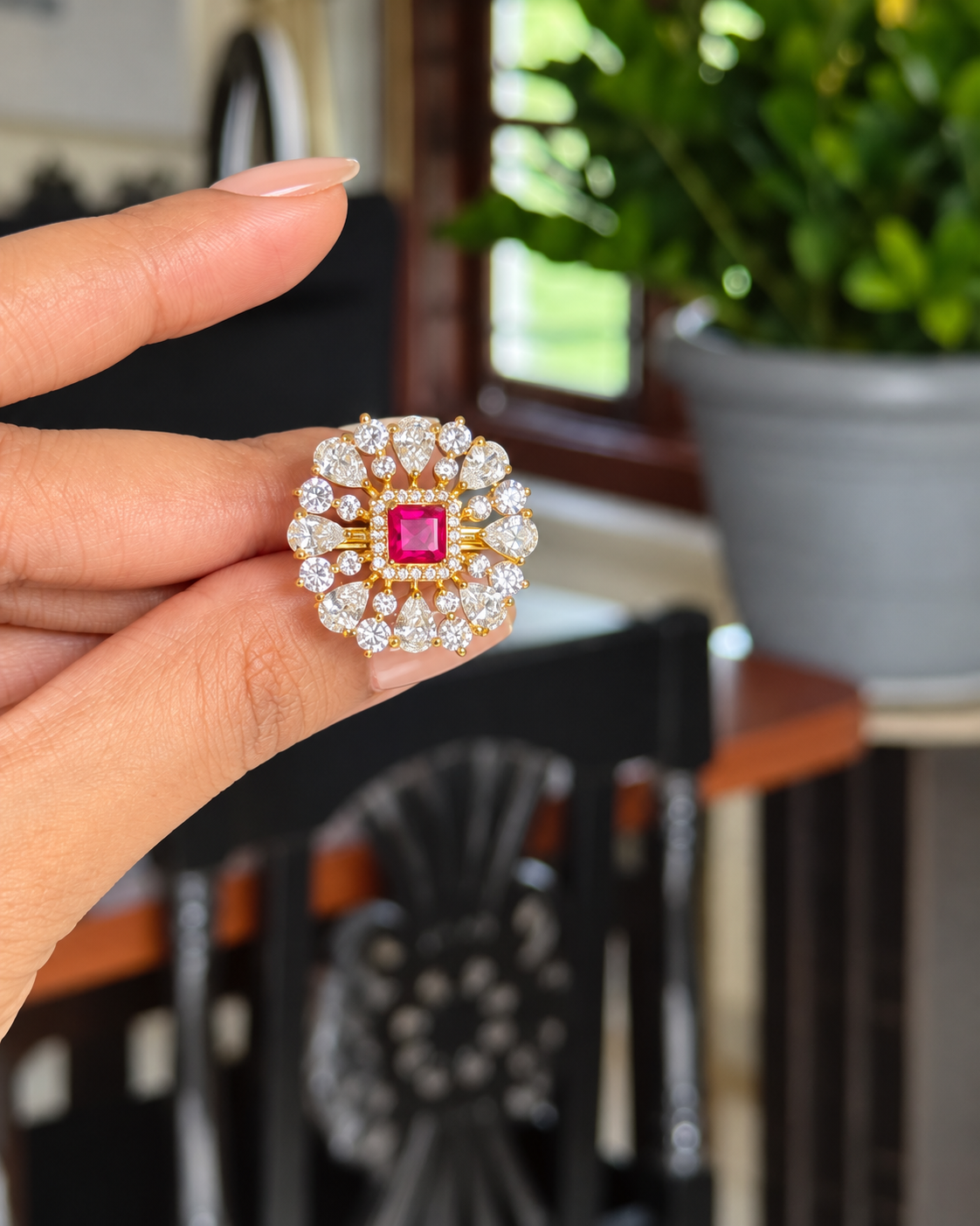 Red onyx floral halo cocktail ring with pear-shaped white stones, holding on hand