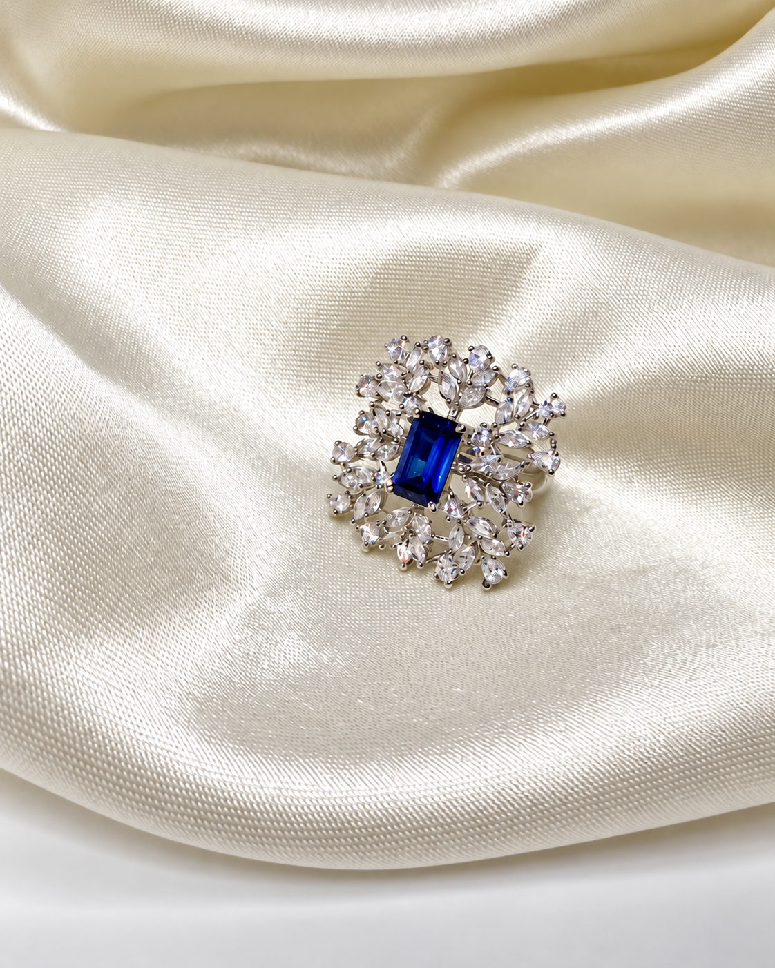 Sapphire Snowflake Cocktail Ring with an openwork silver-tone design on ivory fabric